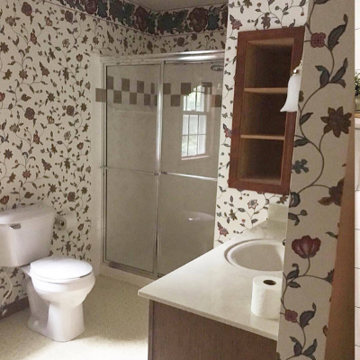 wallpapered bathroom, sink, shower and comode