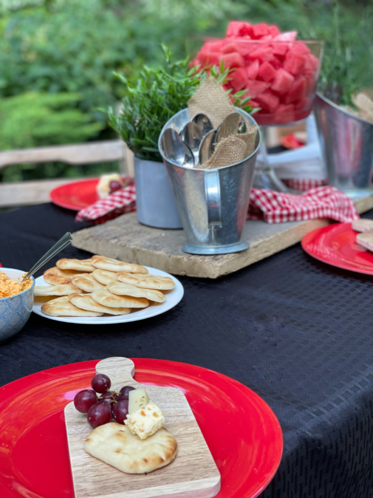 red plates on a black table cloth in the lawn

