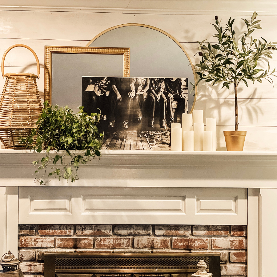 mantel with gold frames, candles and plants